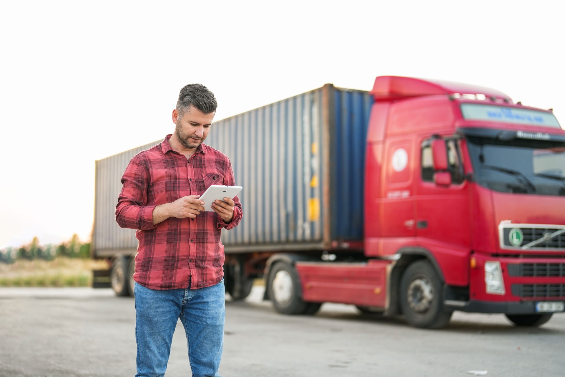 man looking at his tablet in front of red truck